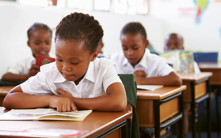 Young children sitting at desks in school reading